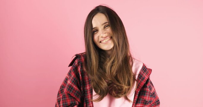 Happy attractive brunette woman look camera showing shape heart with hands, girl wear red plaid shirt isolated on pink background. Love, romantic concept.