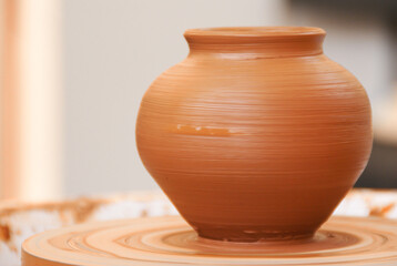 Freshly molded clay pot on a potter's wheel