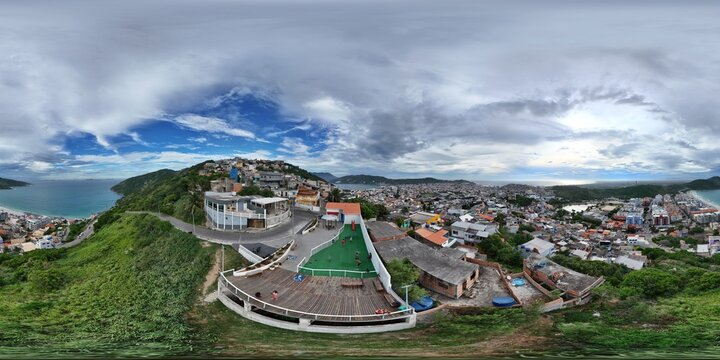 360 aerial photo taken with drone of kids playing in green space atop favela overlooking beach