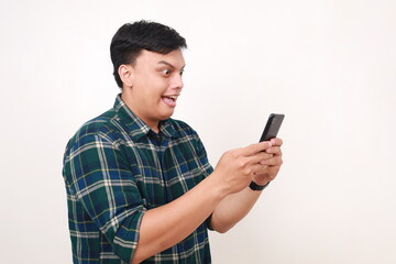 Side view of surprised young asian man while getting a news from his phone