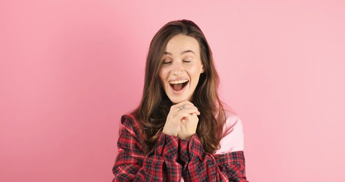 Amazed excited woman win in lottery in red plaid shirt open mouth in surprise looking at camera with big eyes, shocked isolated on pink background. Oh my god wow, yes gesture, win symbol.