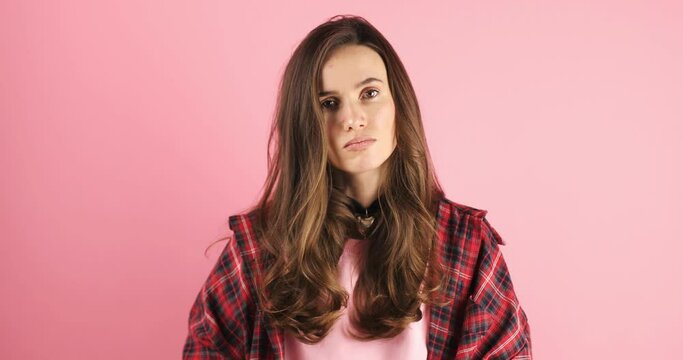 Brunette woman threatens with a fist is isolated on pink background, shows fist has annoyed face expression going to revenge or threaten someone makes serious look. I will show you who is boss.