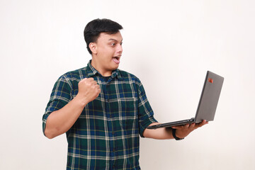 Successful young asian college student clenching hand while holding a laptop