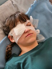 A girl after surgery. Portrait of woman wearing white eye patch as protection after injury. Eye injury emergency first aid medical bandage of a young woman in the hospital