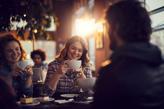 Young people at a cafe enjoying coffee and talking together