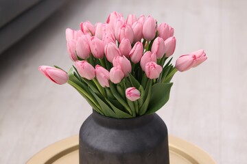 Bouquet of beautiful pink tulips in vase on table indoors