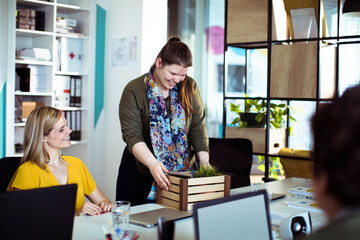 New young female employee bringing box with belongings to office desk
