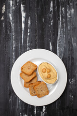 a bowl of hummus dip with mini toasts