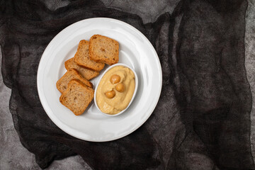 a bowl of hummus dip with mini toasts
