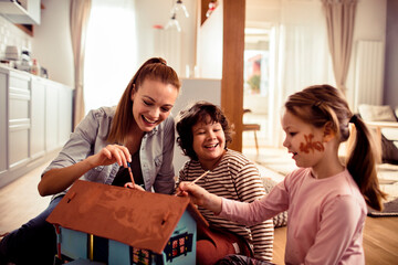 Mother and children painting a playhouse together at home