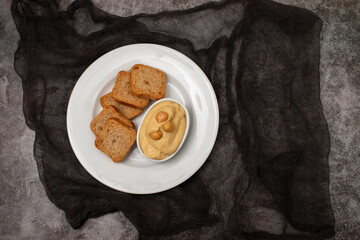 a bowl of hummus dip with mini toasts