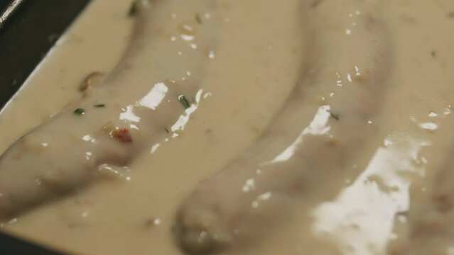 Raw sausages in creamy white bechamel sauce. Close up.