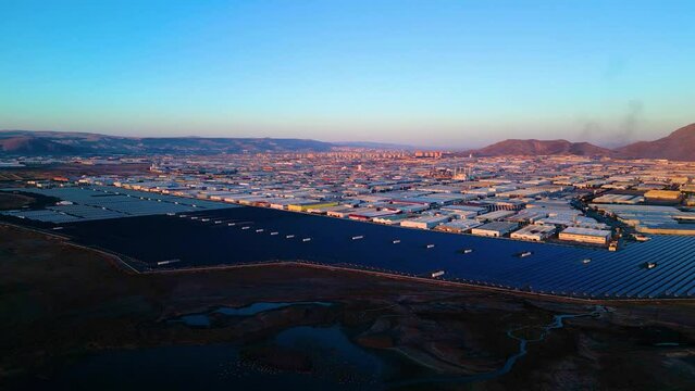 Evening aerial view of factories and a giant solar energy field