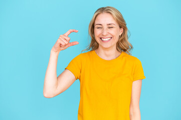 Young woman laughing and showing small size gesture with hand