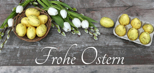 Blumenstrauß mit gelben Ostereiern auf schäbigen Holzbrett mit dem Text Frohe Ostern.