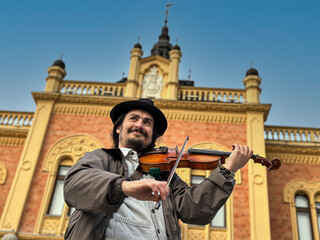 man with hat playing violin on the street, street musician