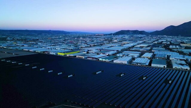 Evening aerial view of factories and a giant solar energy field