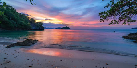 Fototapeten Breathtaking view of a tropical beach at sunset with vibrant sky colors reflecting on the calm sea and silhouettes of islands © Daniel