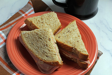 Cold meat sandwich on multigrain bread with coffee.