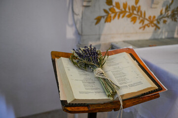 Une bible ouverte avec un bouquet de fleurs séches dans une chapelle et un rameau d'olivier dans...