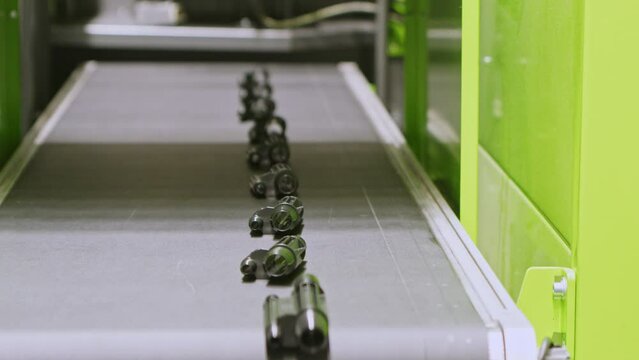 Plastic car parts move on conveyor after production in injection moulding machine. Automation in modern automotive facility.