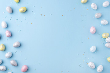 Festive Easter background. Multicoloured Easter eggs and flowers on a blue table. Card with a place...
