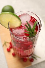 Tasty cranberry cocktail with rosemary and lime in glass on table, closeup