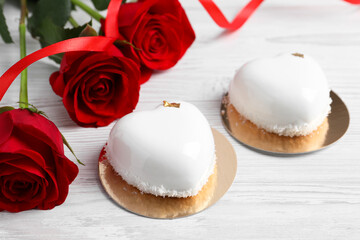 St. Valentine's Day. Delicious heart shaped cakes and roses on white wooden table, closeup
