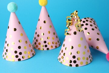 Pink party hats and serpentine streamers on light blue background