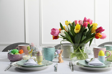 Easter celebration. Festive table setting with beautiful flowers and painted eggs