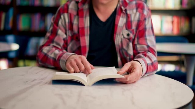 male sits in a scientific and technical library reads a book and prepares write a dissertation