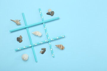 Tic tac toe game made with sea treasures on light blue background, top view