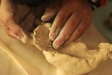 Child's hands sculpts a figurine from clay
