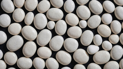 Natural stone background. Multicolored polished white pebbles are randomly stacked on a black background. Smooth flat river pebbles. Full frame shot of rocks. Top view. Close-up.