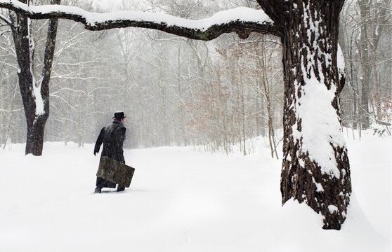 retro. man with suitcase walking in snow forest