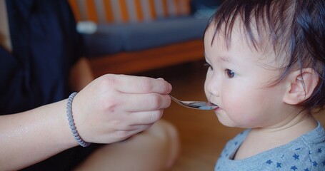 An eager toddler opens wide for a spoonful of food during a messy yet joyful feeding time at home