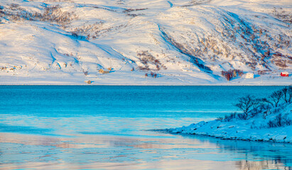Beautiful winter landscape with red house and red cabin - Arctic city of Tromso - Breaking blue ice...