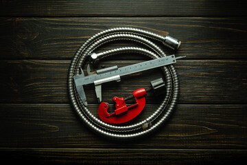 Flexible hose and repair tools on a black vintage table. Plumbing repair concept