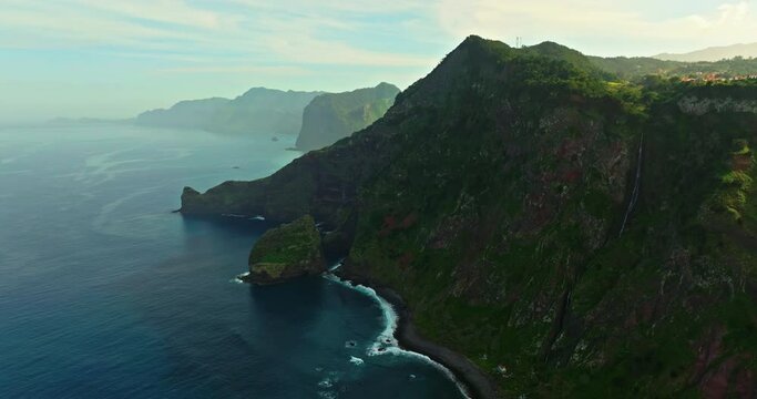 Coast of a green island in the Atlantic Ocean. Madeira landscape with mountains and ocean cliffs aerial drone shot. Breathtaking aerial view of the rugged coastline of Madeira Island