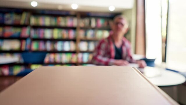 male professor in glasses sits in a scientific and technical library reads a book and prepares write a dissertation