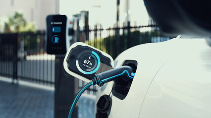 Electric car recharge with EV charger at futuristic car park utilization of charging station...