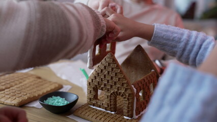 Close-up Gingerbread house, hands building a traditional sugar cookie home during holiday festivities