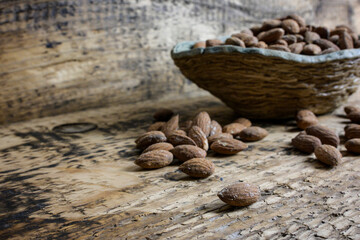 scattered almonds on a wooden background and a side view of a bowl full of almonds