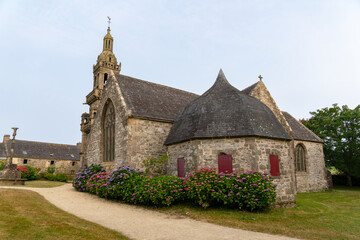 Fototapeta na wymiar En été, les massifs d'hortensias en fleurs bordant le mur de la chapelle offrent un spectacle estival éclatant, illuminant le paysage breton de leur beauté colorée.