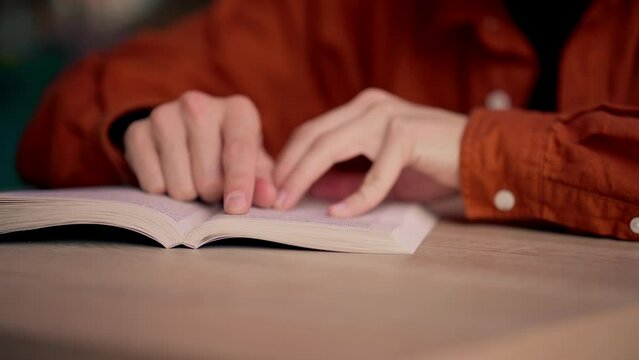 close-up male sits in scientific and technical library reads a book and prepares write a dissertation