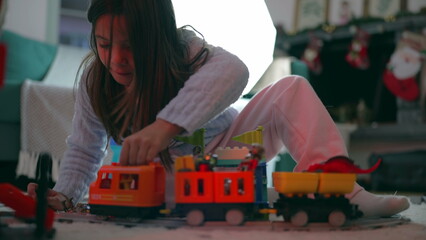 One small girl playing with train toy at home floor. 8 year old child engrossed in imaginative play