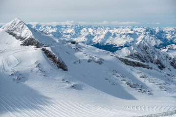 Alpine landscape with peaks covered by snow and clouds, beautiful colors at the top of a glacier.