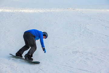 a snowboarder in a blue sweatshirt and helmet rides on a snowy slope