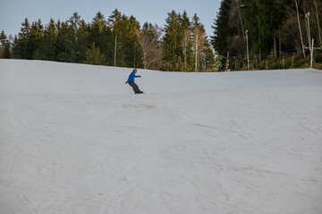 a snowboarder in a blue sweatshirt and helmet rides on a snowy slope