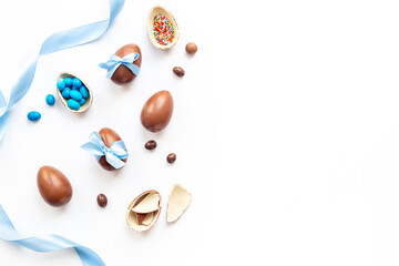 Happy Easter card. Chocolate Easter eggs in blue ribbon with sweets
